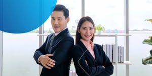 Man and woman standing back to back with arms crossed smiling at camera