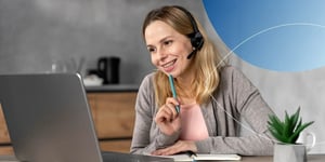 Woman sitting at desk wearing headset and smiling to her laptop