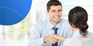 Man shaking hands with a woman in front of him smiling