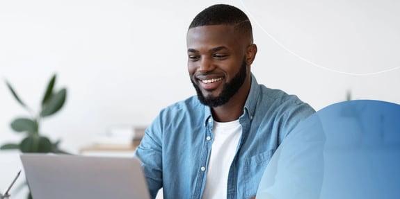 man in blue shirt working on his laptop smiling
