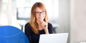 woman smiling with hand to her chin looking into laptop