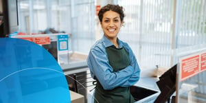 woman wearing apron with her arms crossed smiling into camera