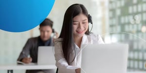 woman wearing headset speaking into laptop and smiling