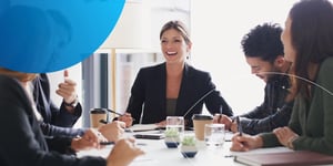 woman smiling at her colleagues sitting at meeting table
